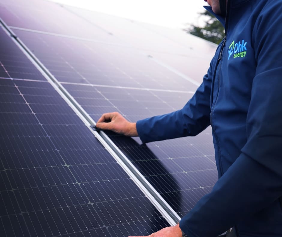 person with ohk energy jacket with hands on to an solar panel array