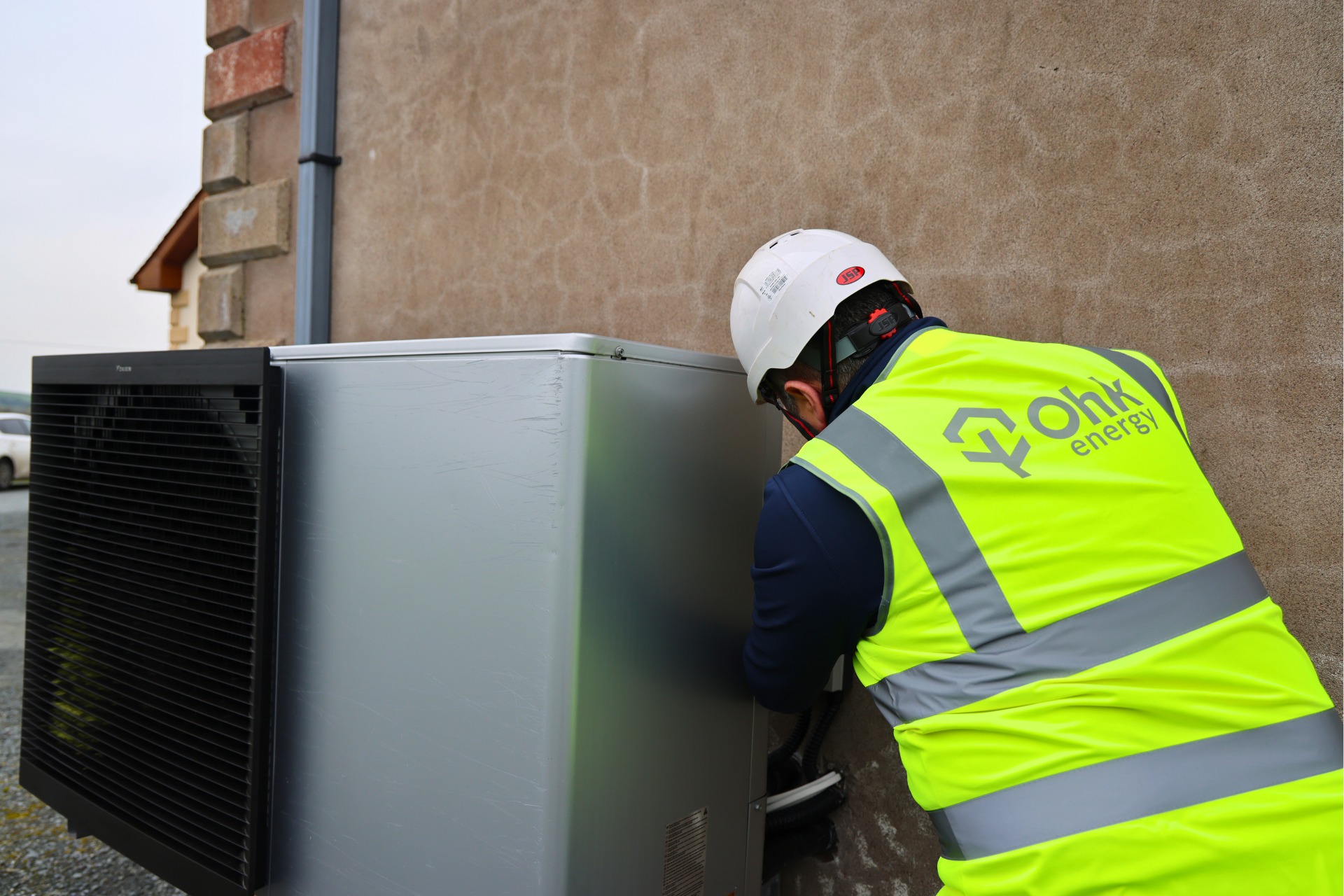 Choosing A Heat Pump Image showing an Ohk energy heat pump installer working on an air to water heat pump.