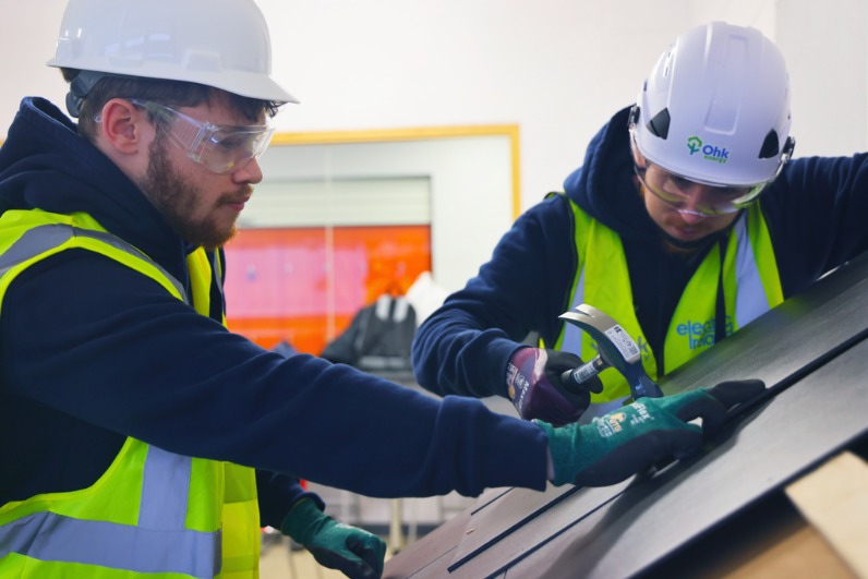 Renewable Construction Technologies Traineeship Student Image showing 2 students, with Ohk energy PPE, getting practical experience as they work on roof tiles.