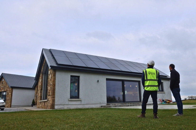 Home Retrofit Example Image showing an Ohk energy employee and customer outside a home that was retrofitted with solar panels.