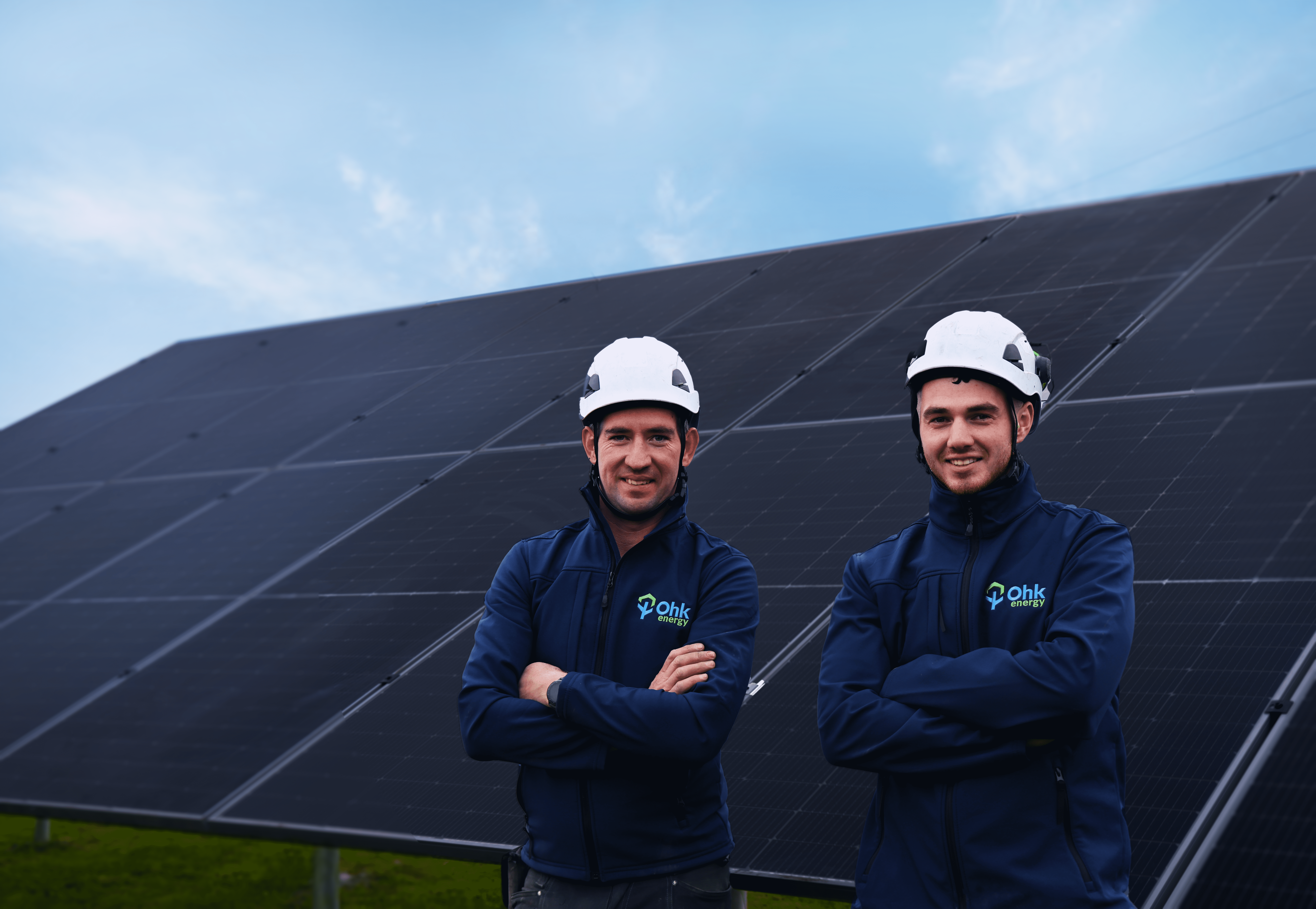 Two men in front of a ground mounted solar pv system with arms folded
