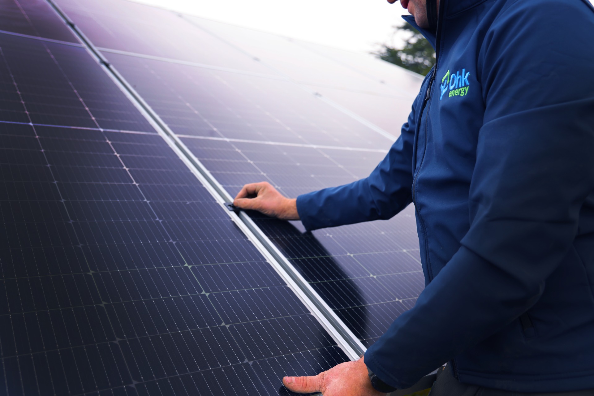 Best Place In Cork For Solar Panels Featured Image showing an Ohk energy electrician installing solar panels.