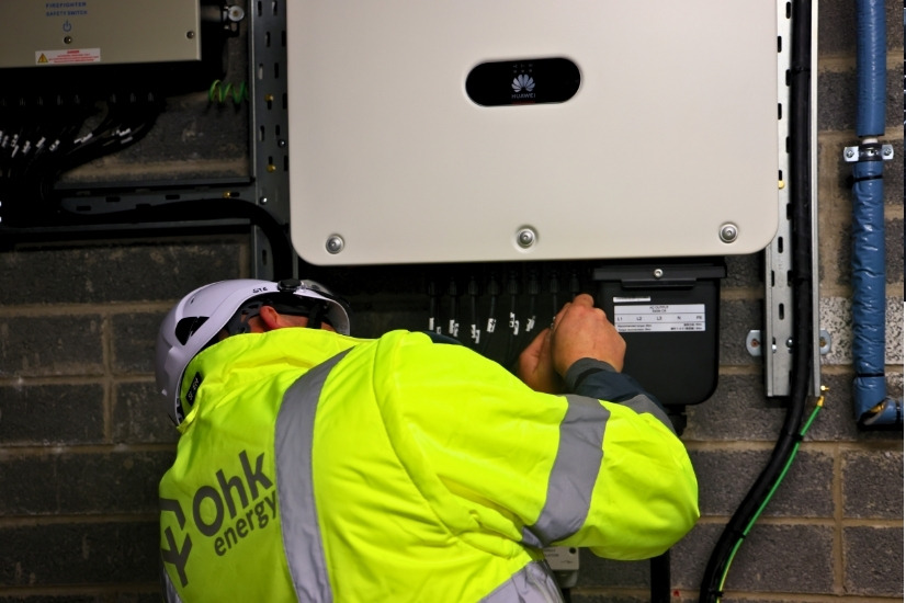 Solar PV Panels Inverter Image showing an Ohk energy electrician installing a solar PV inverter.