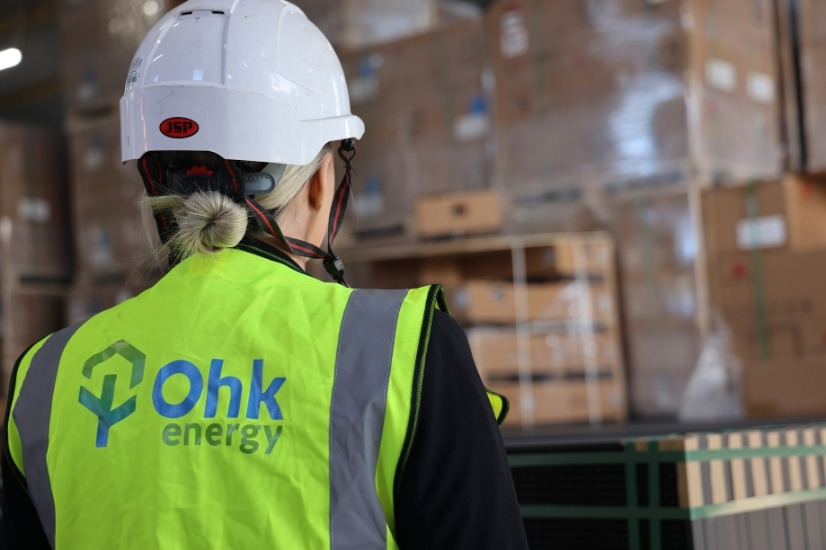 Solar Panels Cost Example Image showing an Ohk energy employee in our warehouse full of solar panels and equipment.