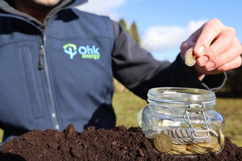 Solar Panels Cost Saving Tips Image showing an Ohk energy electrician placing euros into a savings jar.
