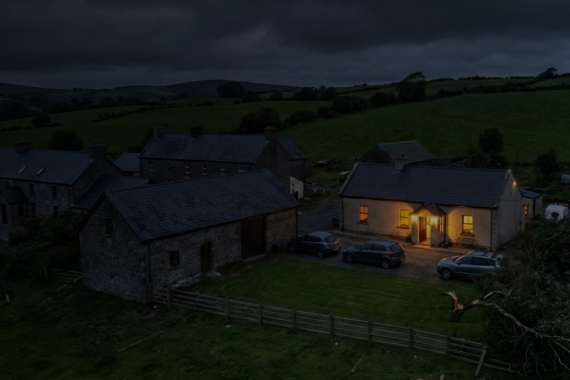 Storm Konnect image showing rural houses in Ireland during a storm with fallen trees at night and a power outage, however, one house still has power due to Ohk energy's Storm Konnect backup power solution.