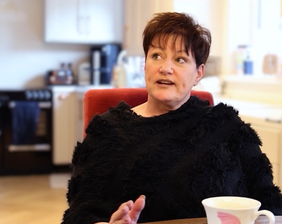 One Stop Shop Service Case Study Video Preview Image of Suzanne O’Neill, Ohk energy One Stop Shop Service customer, sitting at a table in her home speaking sharing her experience and house energy retrofit works completed.
